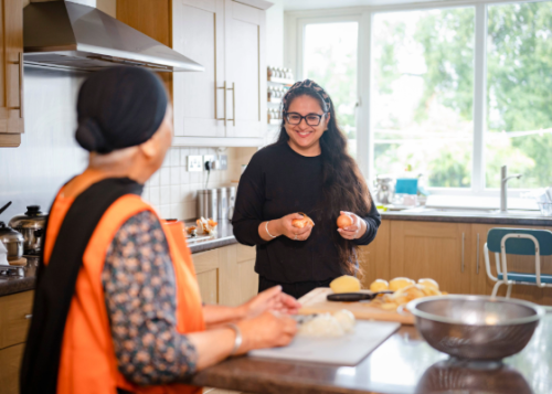 Two women peeling vegetables in a kitchen.
