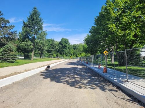View of Centennial Park Road looking north near existing chalet building showing the new sidewalk on the east side of Centennial Park Road and the preparation of the new multiuse trail on the west side.