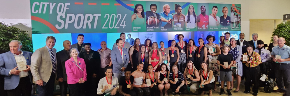 The Sports Hall of Honour 2024 inductees stand with their awards in front of the recognition wall at the Toronto Pan Am Sports Centre, during the inductee ceremony in June 2024.