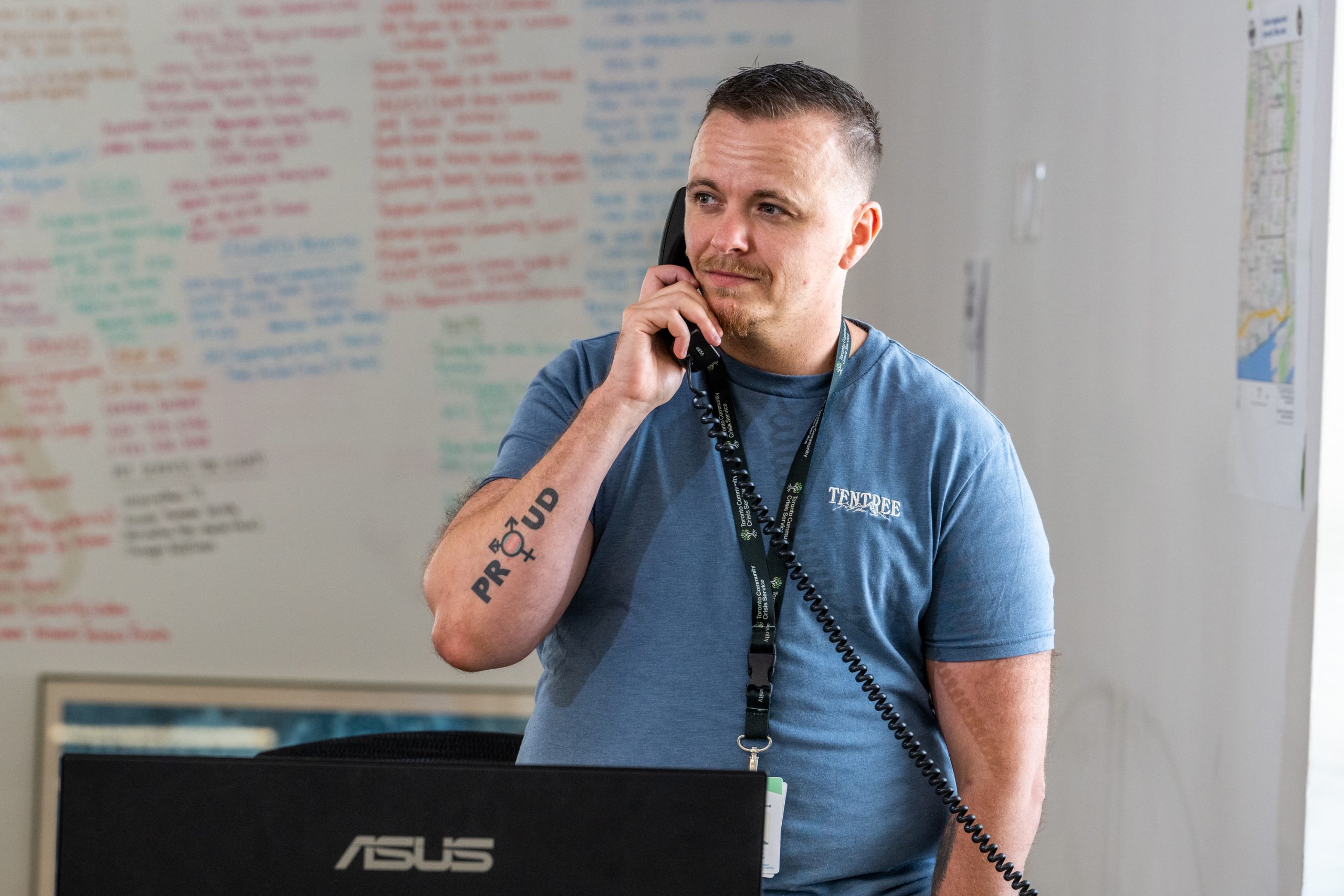 A man speaking on the phone standing in front of a white board.