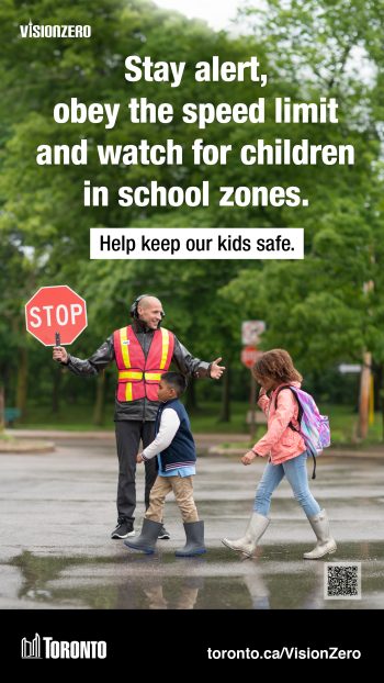 Image of two school children crossing the road with the help of a school crossing guard. 
