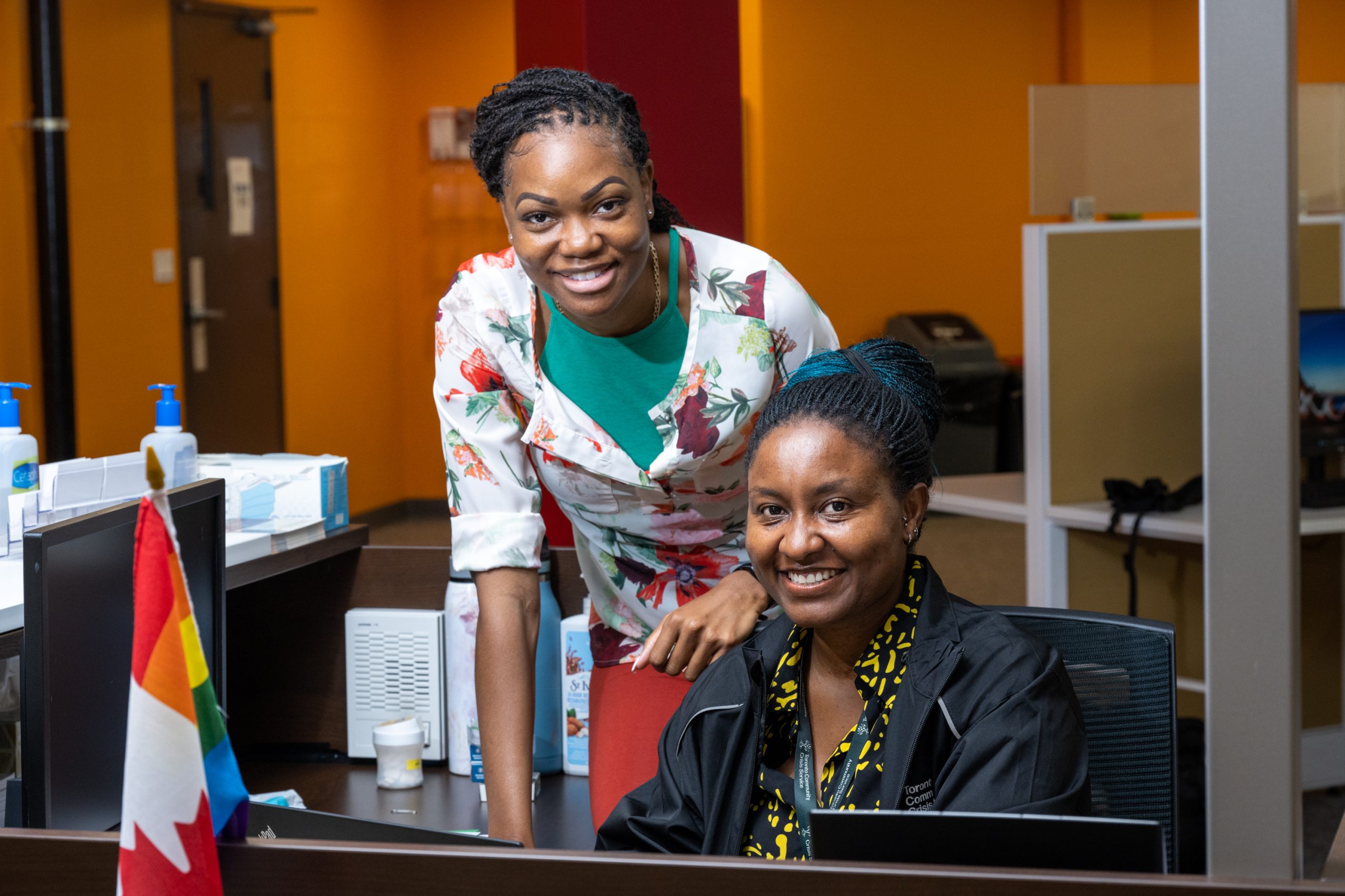 Tow women posing for a photo at a desk.