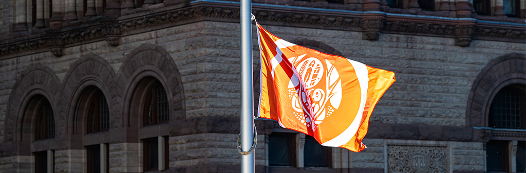 Close up of orange Survivors Flag flying on flagpole.