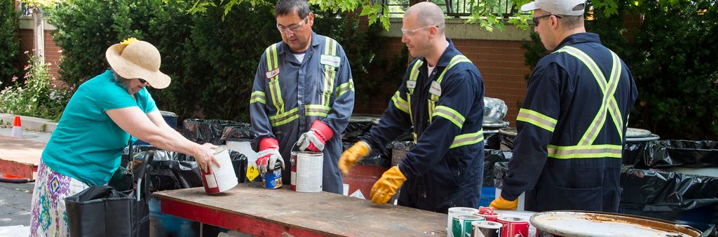 A woman dropping off paint cans and other household hazardous waste at a Community Environment Day in Toronto.