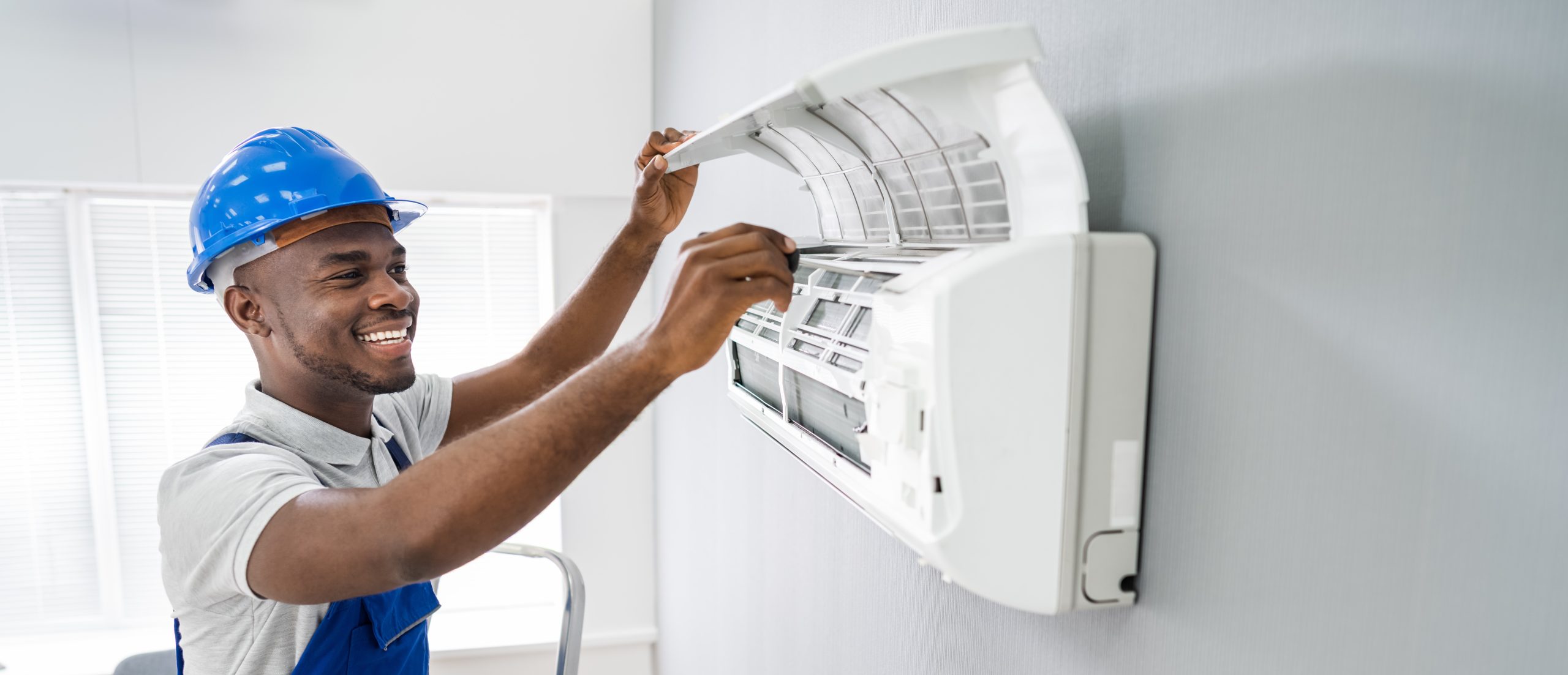A colour image of an HVAC professional installing a heat pump inside of a living room