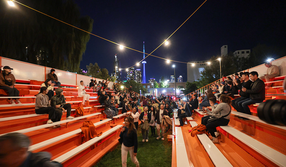 Crowds of people sit on two opposing orange grand stands.