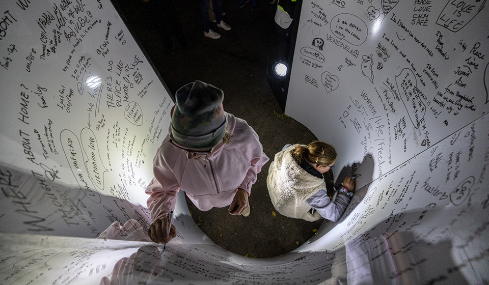 Two people seen from above draw and write on a curved wall