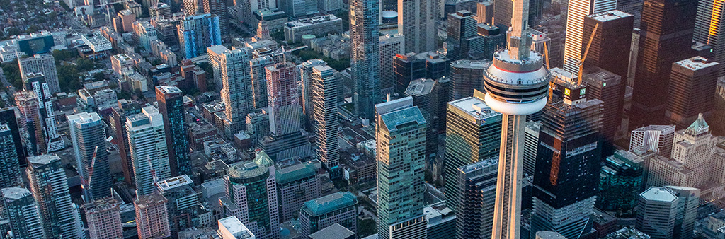 Aerial perspective of skyscrapers and the CN Tower above downtown Toronto on a sunny day.