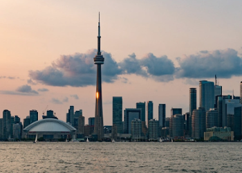 Toronto skyline with a sunset and clouds over the CN Tower and city buildings.