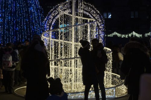 Couple embracing in front of lights display.