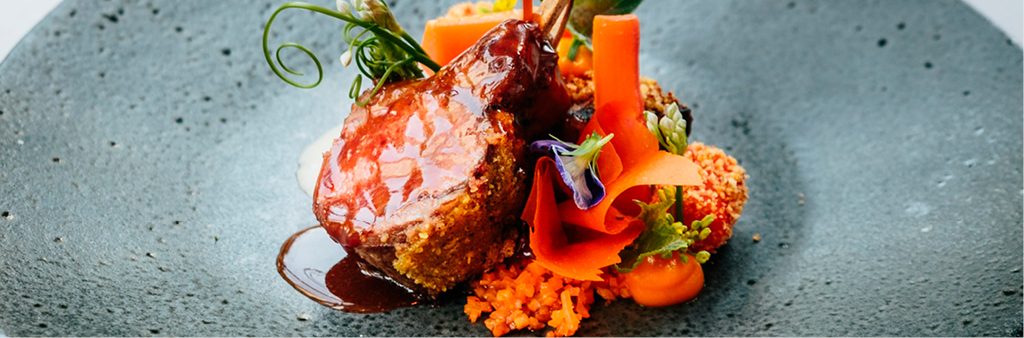 A lamb dinner plated artfully with colourful garnishes.