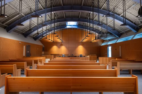 An image from the back of a courtroom looking towards the front. Rows of benches in foreground with the section for court staff at the top of image.