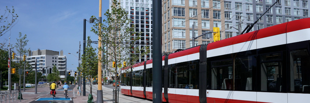 City street in Toronto showing a red streetcar and two cyclists.