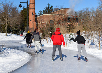 Skaters gliding along a skate trail near a brick building.