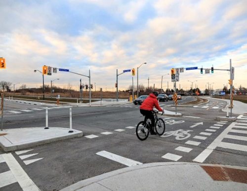 Image of a person cycling through a protected intersection with mountable curbs and shorter crossing distances