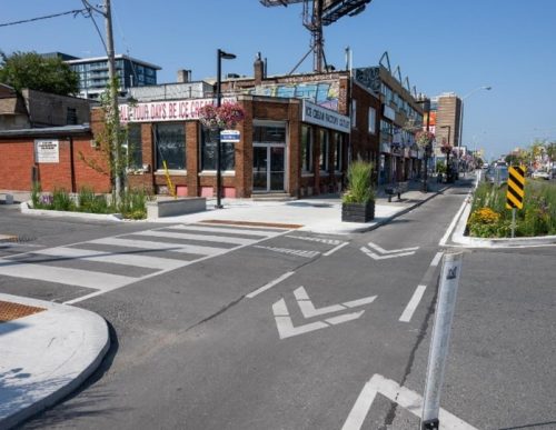 Image of a curb extension example at a side street with raised crosswalks and cycle tracks