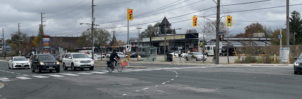 A major intersection in Thistletown neighbourhood, with cars waiting for the signal and a person cycling crossing the street