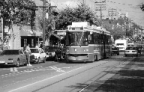 Streetcar on the road with cars parked on the street. 