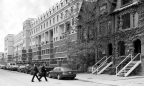 Lofts lining the street with cars parked out front and two women crossing the street.