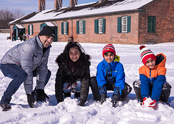 Three children and an adult playing in the snow at Fort York.