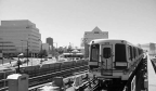 A subway outside on its tracks with a couple of buildings in the background.