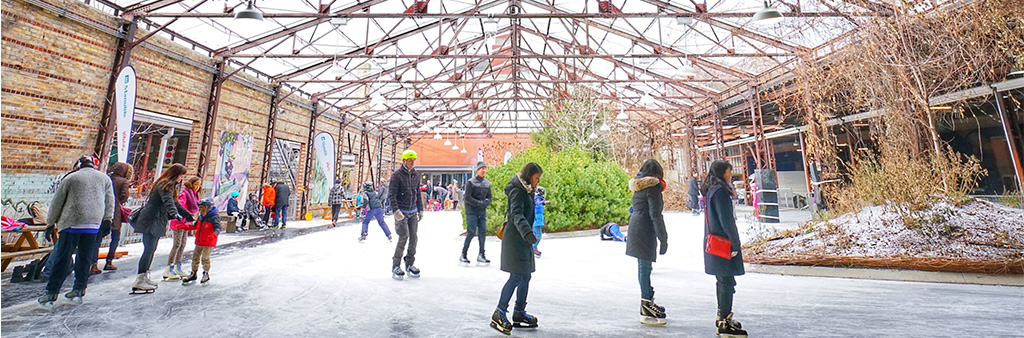 People skating around Evergreen Brickworks with an open air barn like roof overhead.