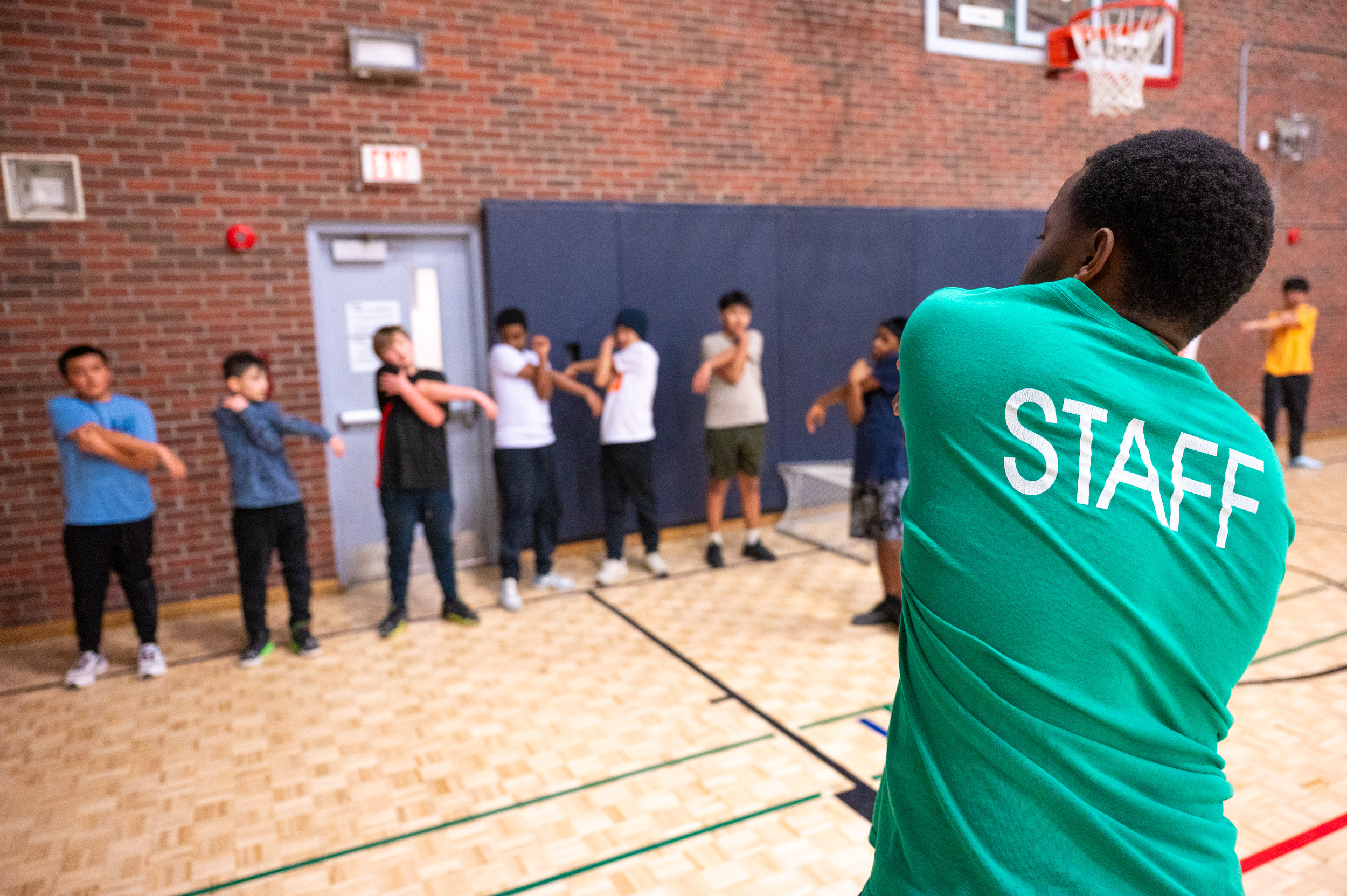 City of Toronto staff and group of youth stretching in the gymnasium at Masaryk-Cowan Community Recreation Centre.