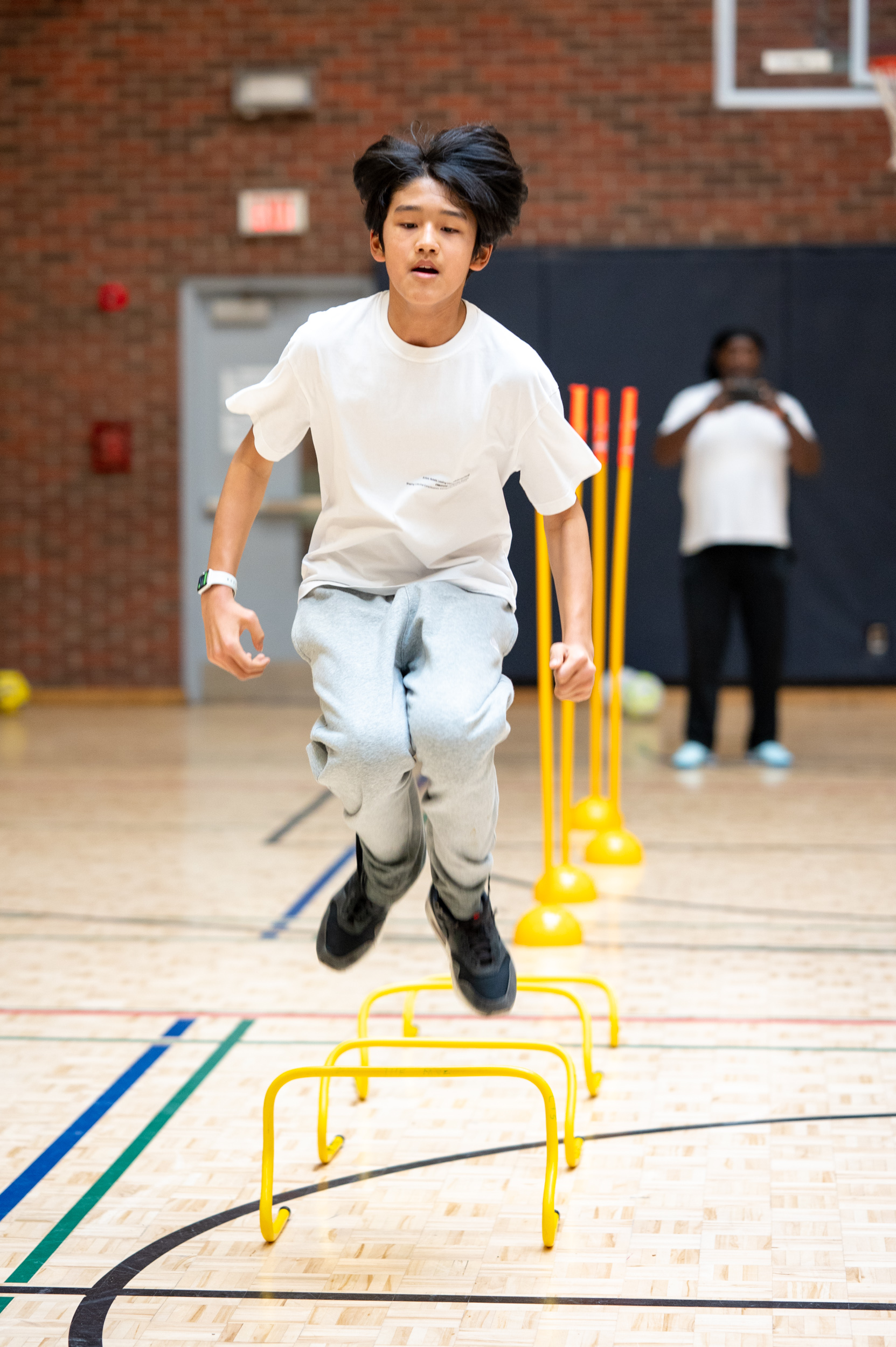 Youth jumping over a rail for a soccer drill at Masaryk-Cowan Community Recreation Centre at an “Improving Well-Being Through Sport” workshop.