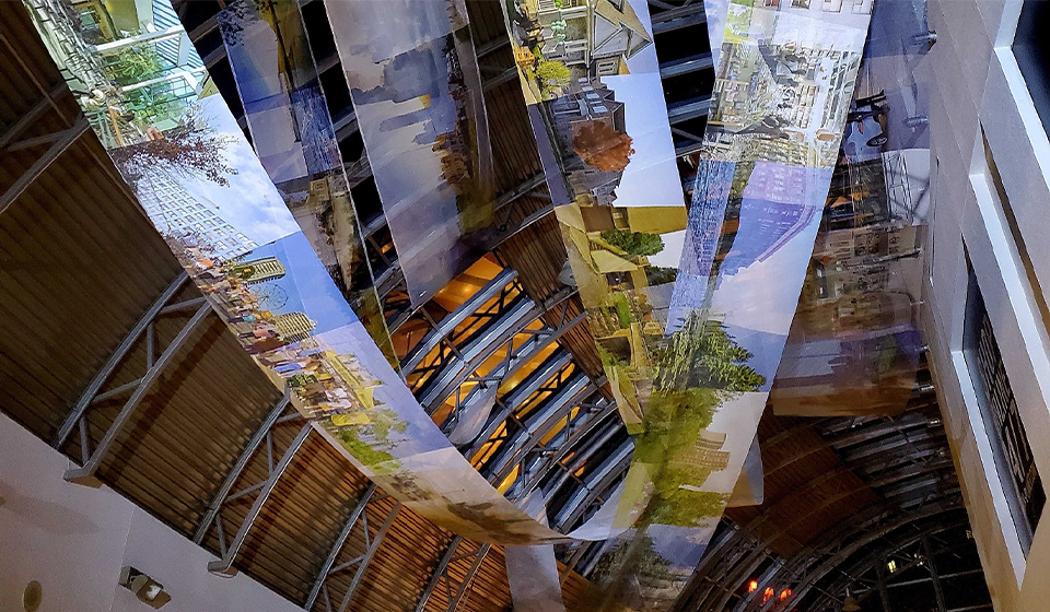 Long cloth banners covered in photographs like a reel of film drapes from the ceiling of a building