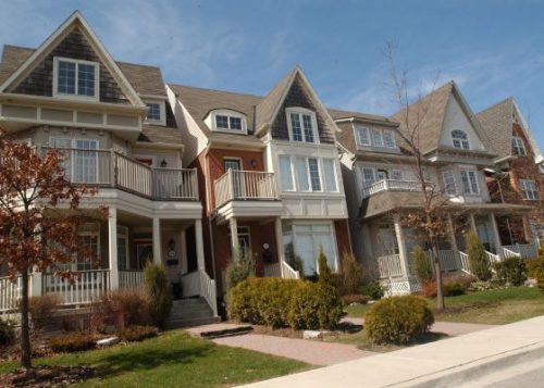 Residential homes on a street showing well-manicured lawns and trees on a fall day.