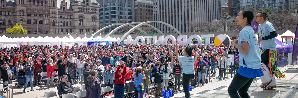 Performers on the stage at Nathan Phillip's Square encouraging a large crowd to participate in an activity