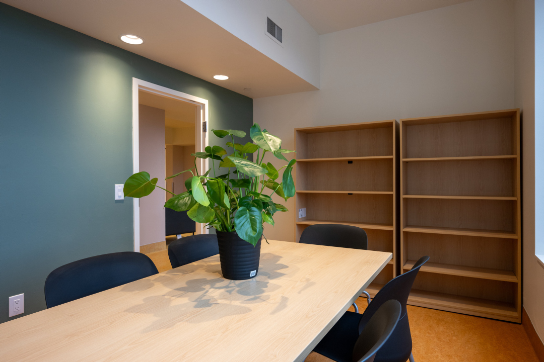 A meeting room with a table, chairs and shelving unit at 25 Canterbury Place.