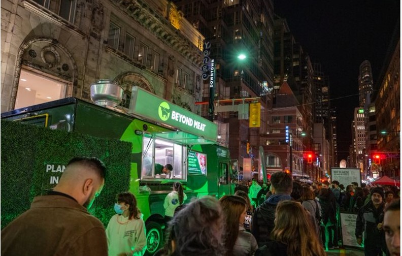Attendees line up at the Beyond Meat food truck where staff serve samples.