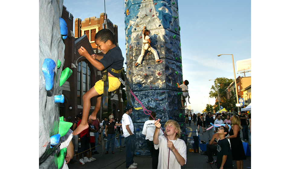 Children rock climb at a street festival
