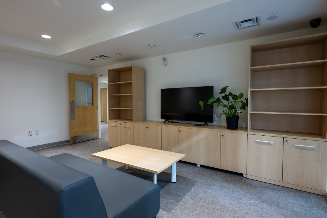 A youth lounge with seating, table, a tv and shelving units at 25 Canterbury Place.