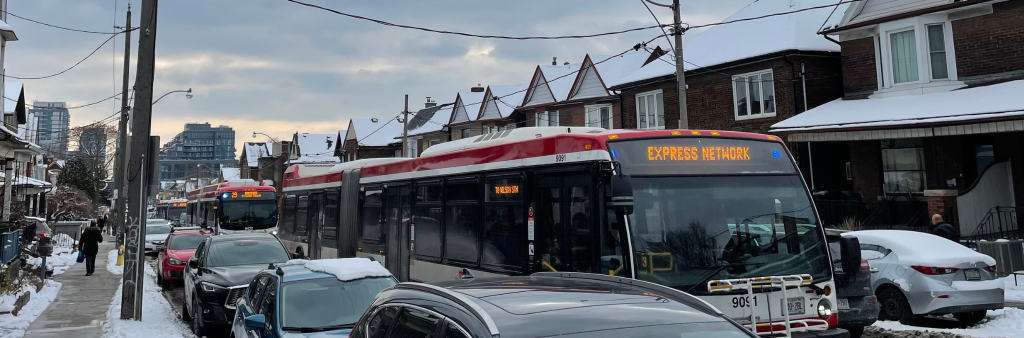 Three Dufferin Buses adjacent to parked cars in the curbside lane