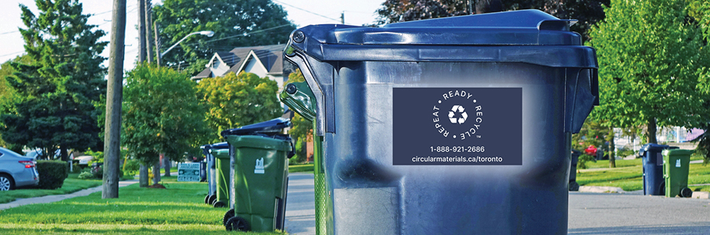 A Blue Bin for recycling with a Circular Materials sticker on it.