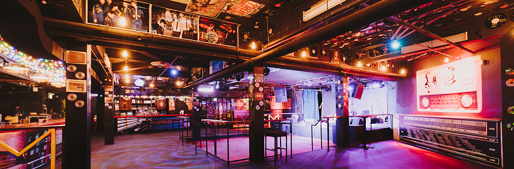 An empty bar with a small stage lit up with colourful lighting.