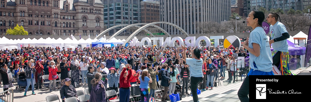 Performers on the stage at Nathan Phillip's Square encouraging a large crowd to participate in an activity. Presented by President's Choice.