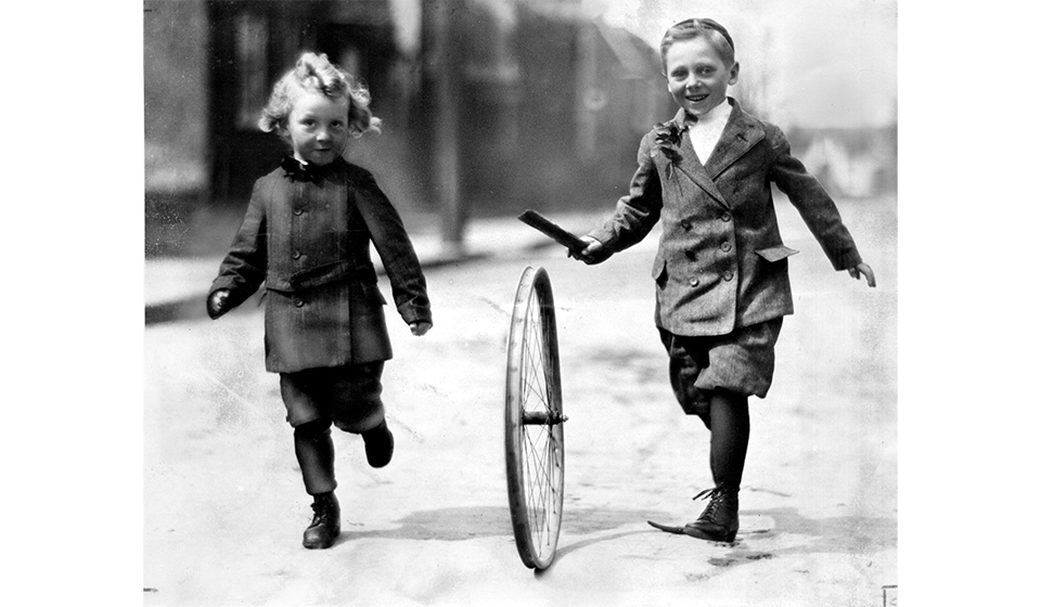 Two children running playing hoop and stick