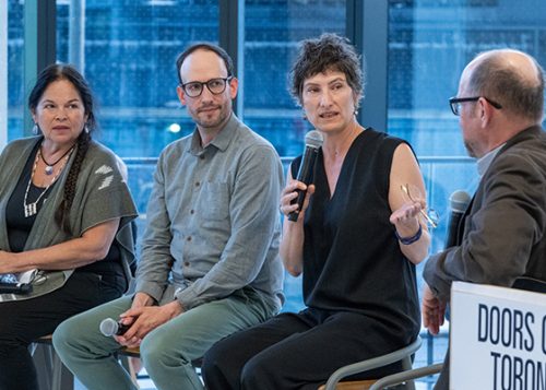 One person speaks into microphone while three other panelists listen.