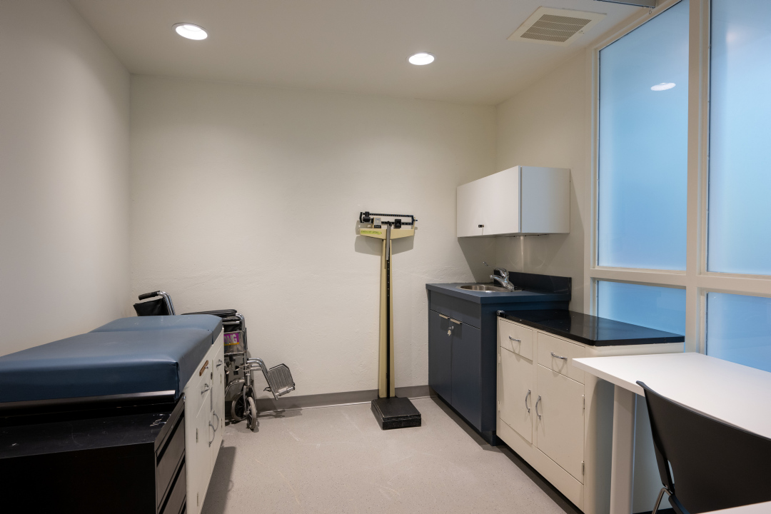 A medical room with an exam table and weigh scale at 25 Canterbury Place.