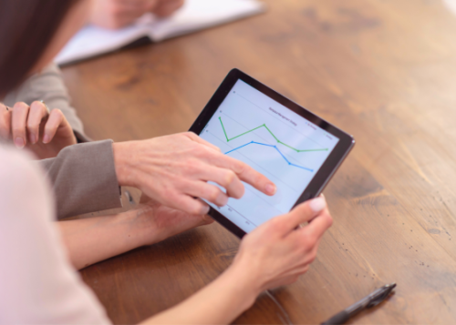 Two people looking at a line graph on a tablet.