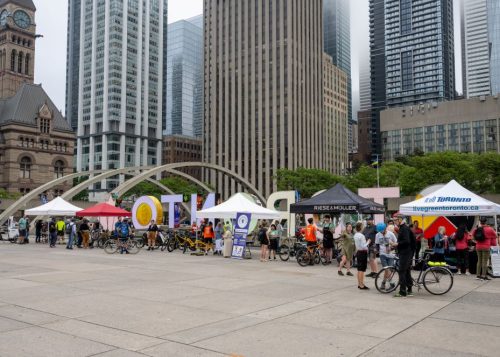 Nathan Philips Square facing south with bicycles and tents in the foreground and tall buildings to the south of Queen street in the rear.