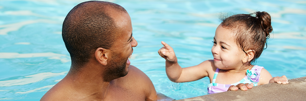 A father and daughter share a joyful moment together in a swimming pool.