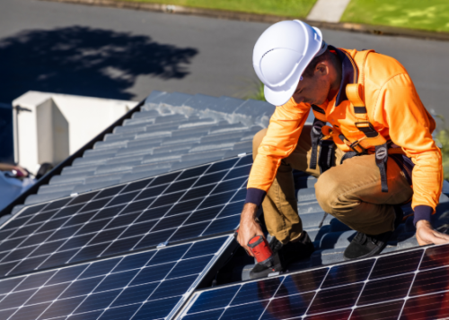 A worker installing solar panels on a roof.