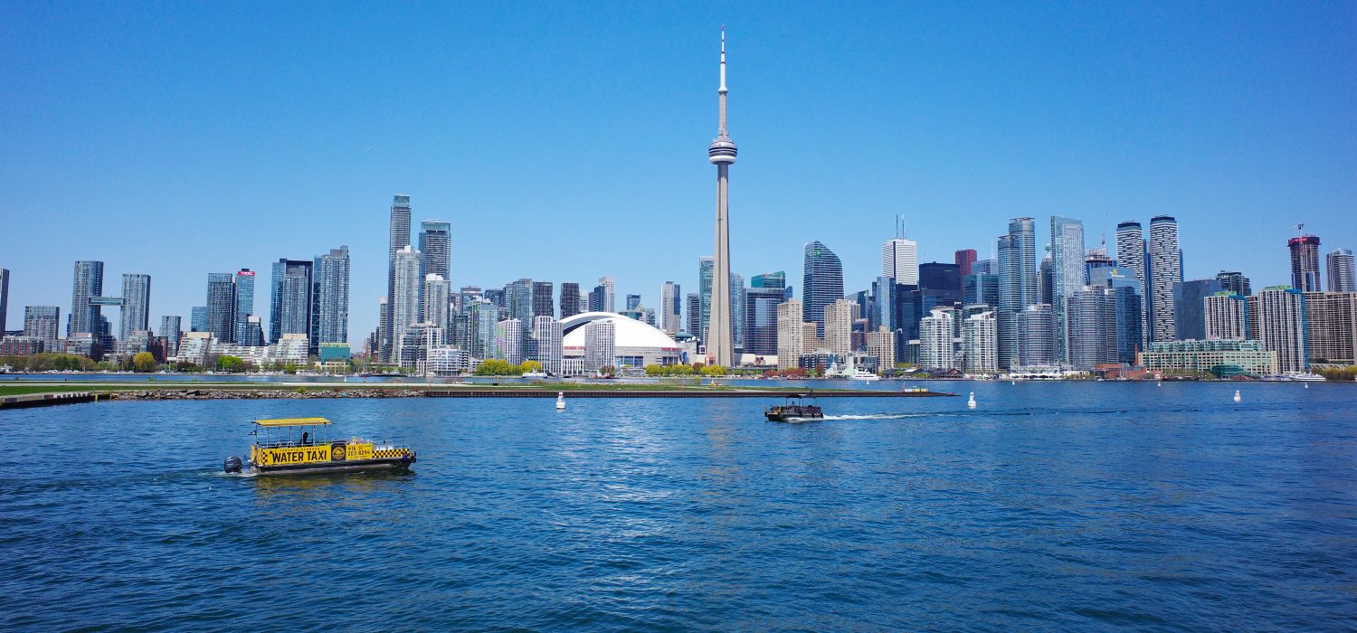 Toronto skyline with CN Tower, Rogers Centre, and boats on Lake Ontario.