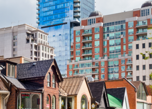 A group of row houses against a backdrop of high-rise buildings