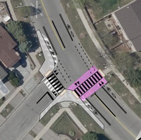 An aerial image of the intersection of Alton Towers Circle and Ingleton Boulevard highlighting the crosswalk on the northside in mauve. Lines are drawn on the road to show a curb extension, repositioning of the crosswalk on Ingleton Boulevard and adjusted lines on the road. 