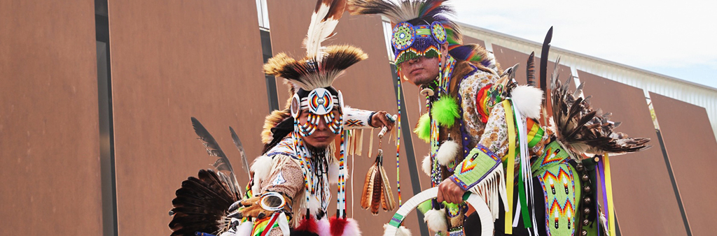 Close up of two dancers in front of a modern metal building.